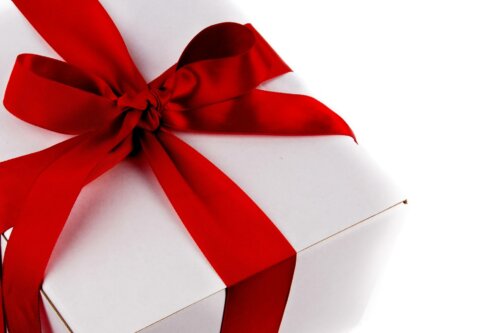 A white Christmas present wrapped in a bright red ribbon