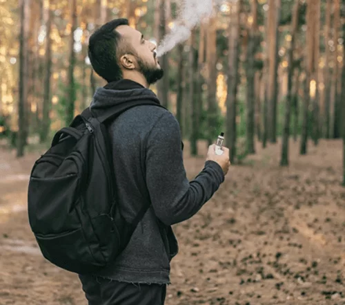 A man vapes in the forest