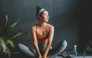 A woman sits on her yoga mate while practicing a yoga pose