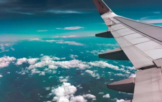 The wing of an airplane high above the clouds