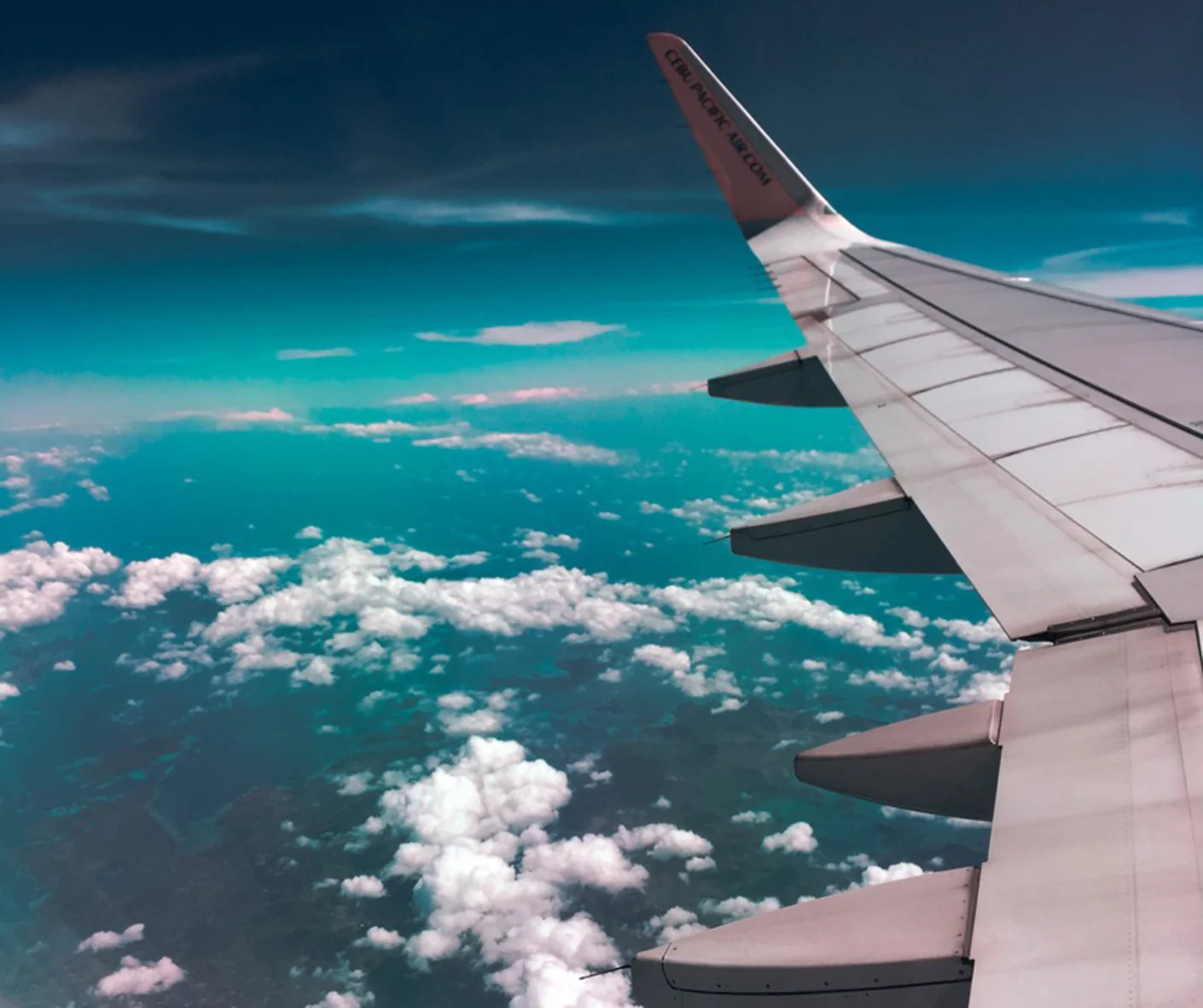 The wing of an airplane high above the clouds