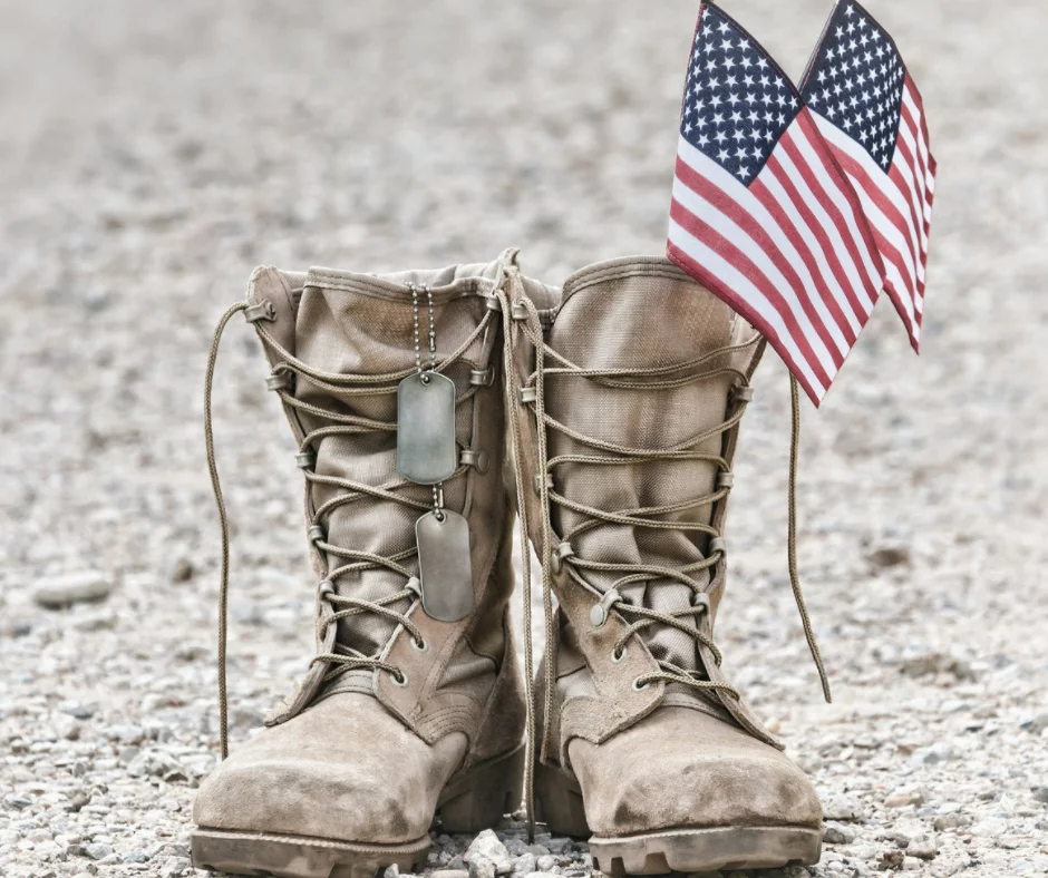 A solider's boots with dog tags and two American flags